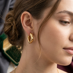 Close-up of a woman wearing gold hoop earrings and a necklace.