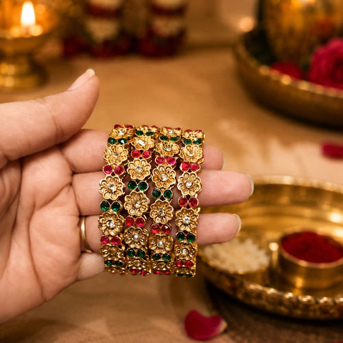 Hand holding a set of decorative gold jewelry with gemstones against a blurred background