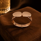 Gold bracelet with two round pads on a brown surface