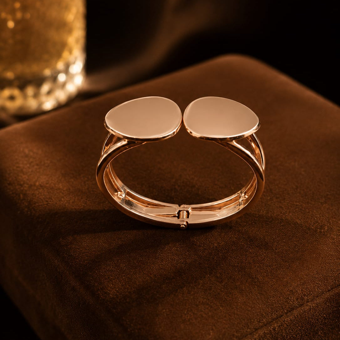 Gold bracelet with two round pads on a brown surface