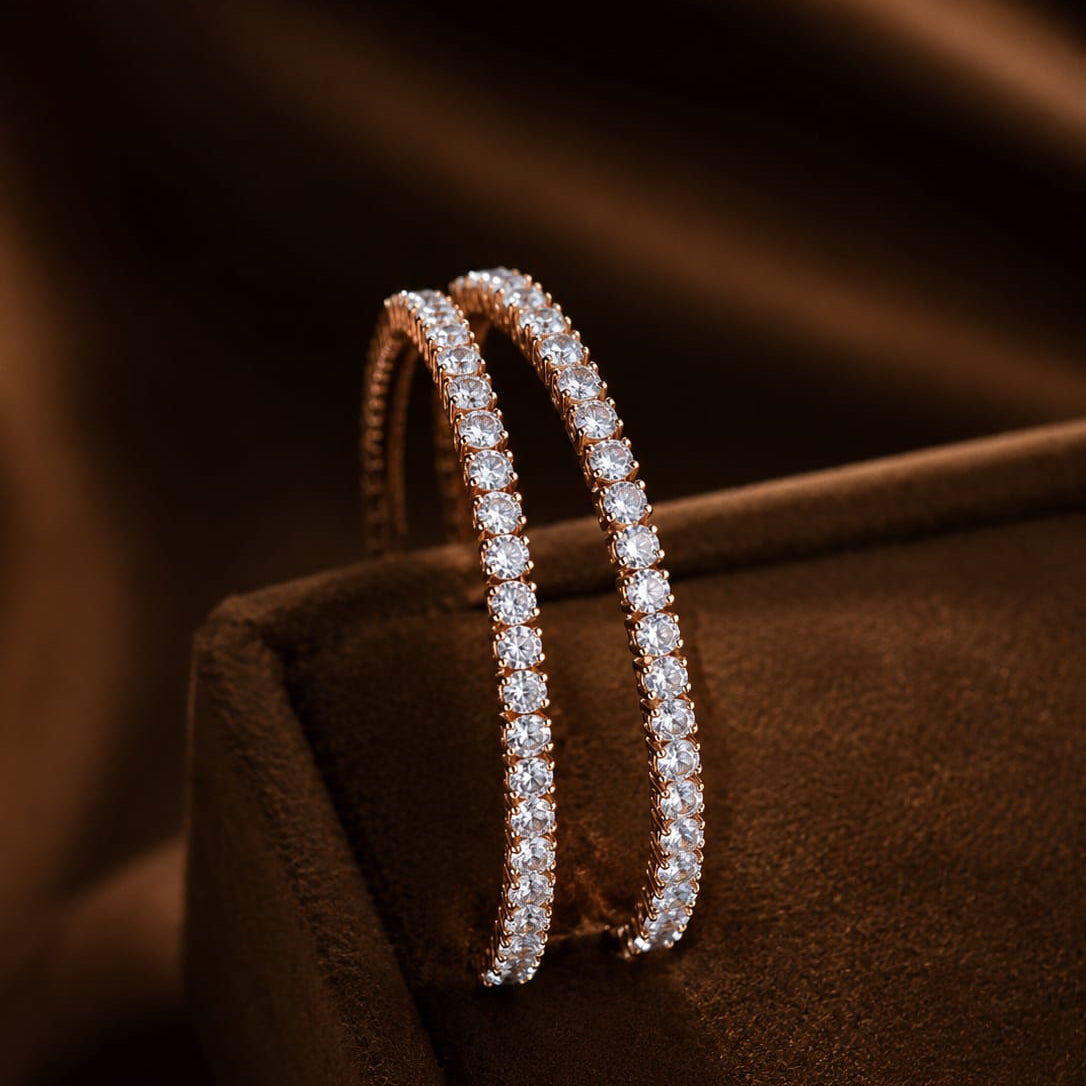 Pair of diamond hoop earrings on a brown cushion with a dark background