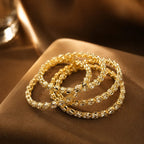 Gold bracelets on a brown surface