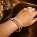 Hand wearing a diamond bracelet and ring on a dark background