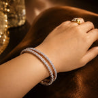 Hand wearing a diamond bracelet and ring on a dark background