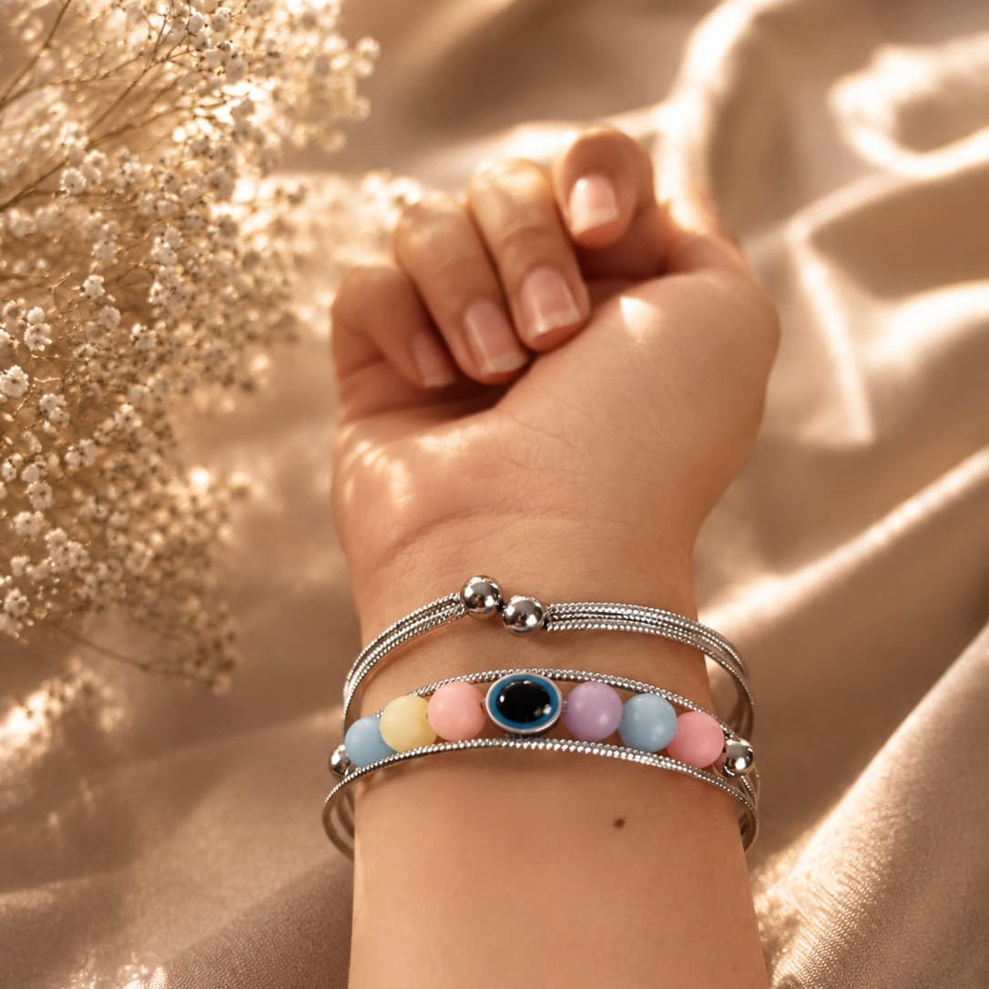 Close-up of a wrist wearing multiple bracelets with colorful beads against a soft, blurred background.