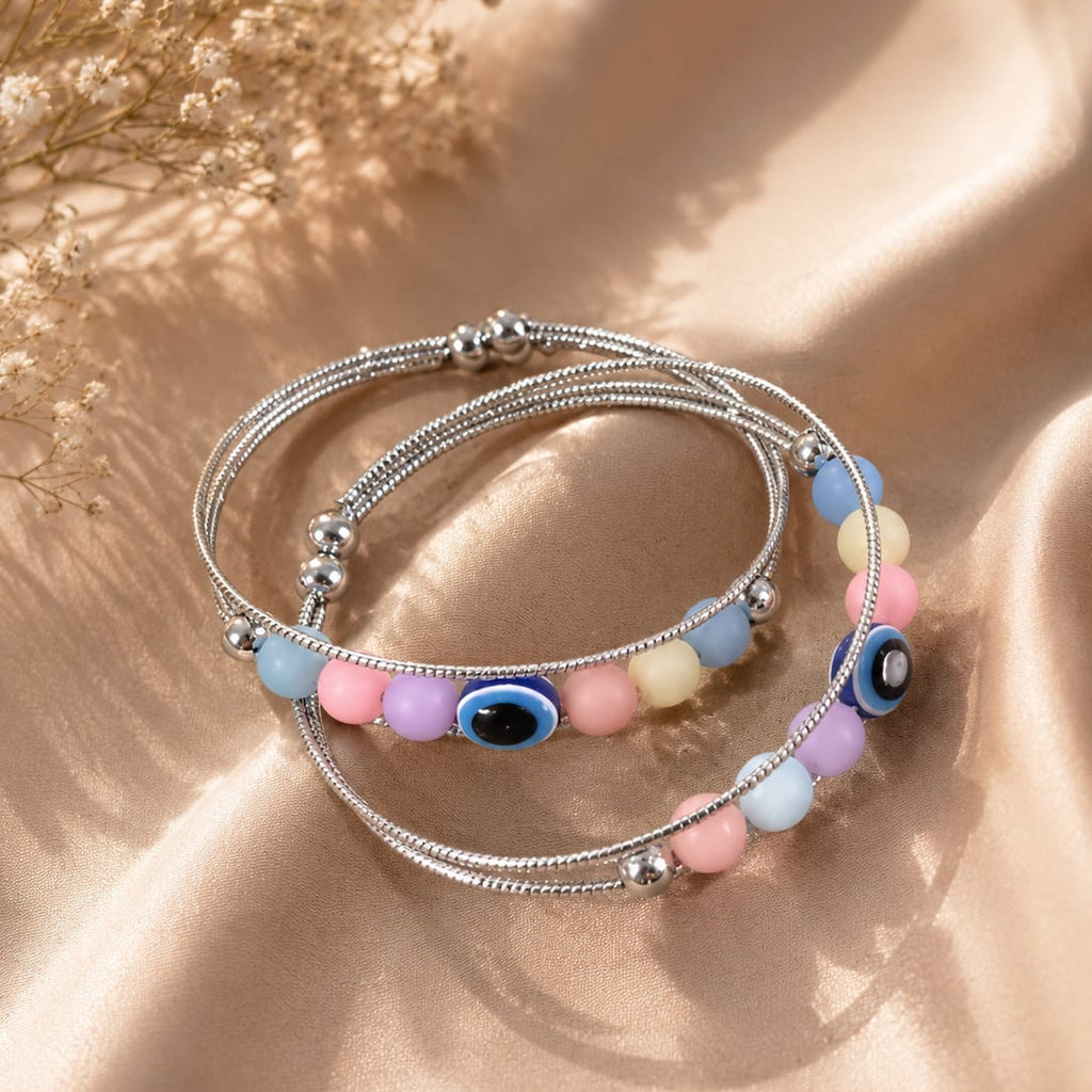 Stack of colorful beaded bracelets on a beige surface with dried flowers.