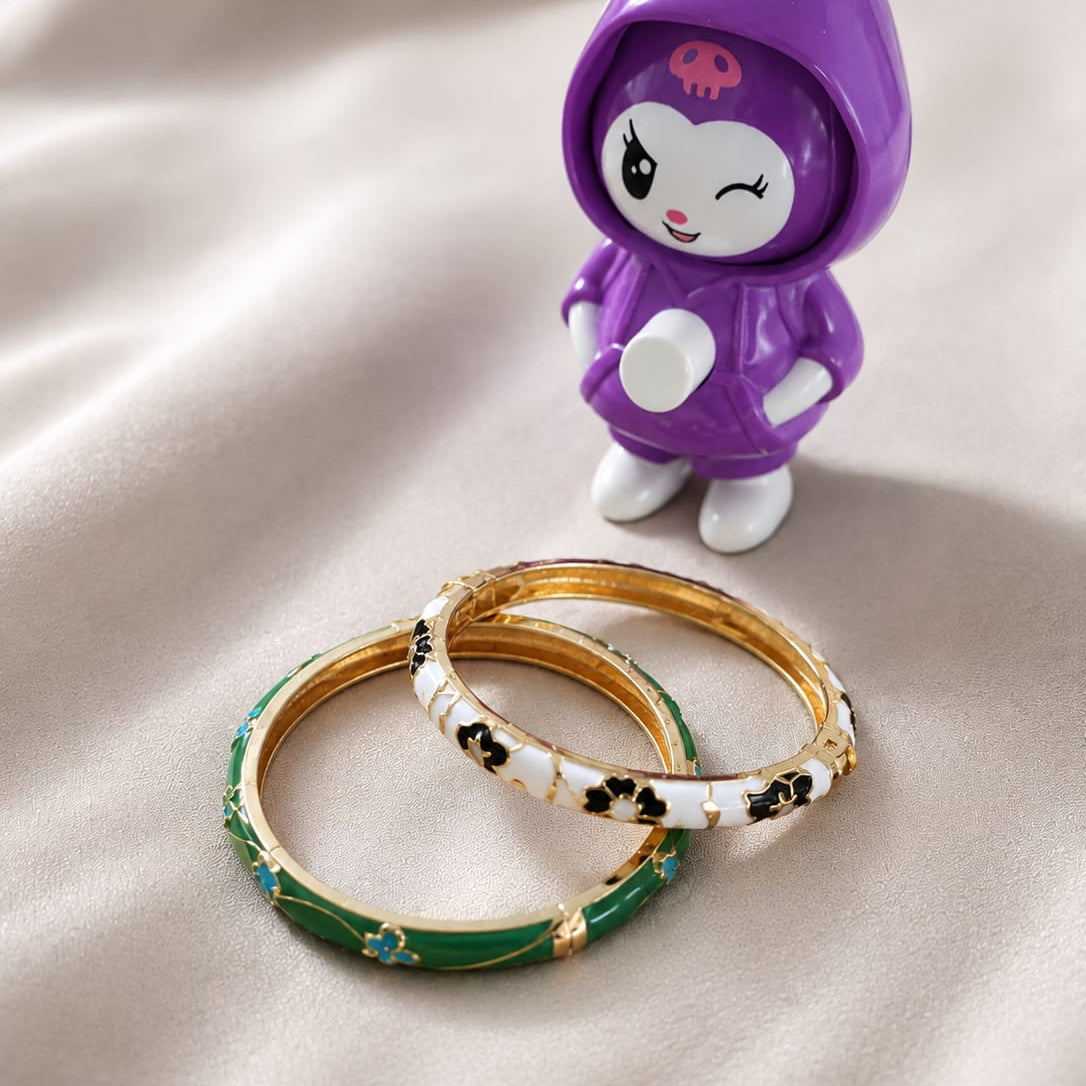 Small figurine in a purple hoodie with a pink face, standing next to two bangles on a beige fabric background.