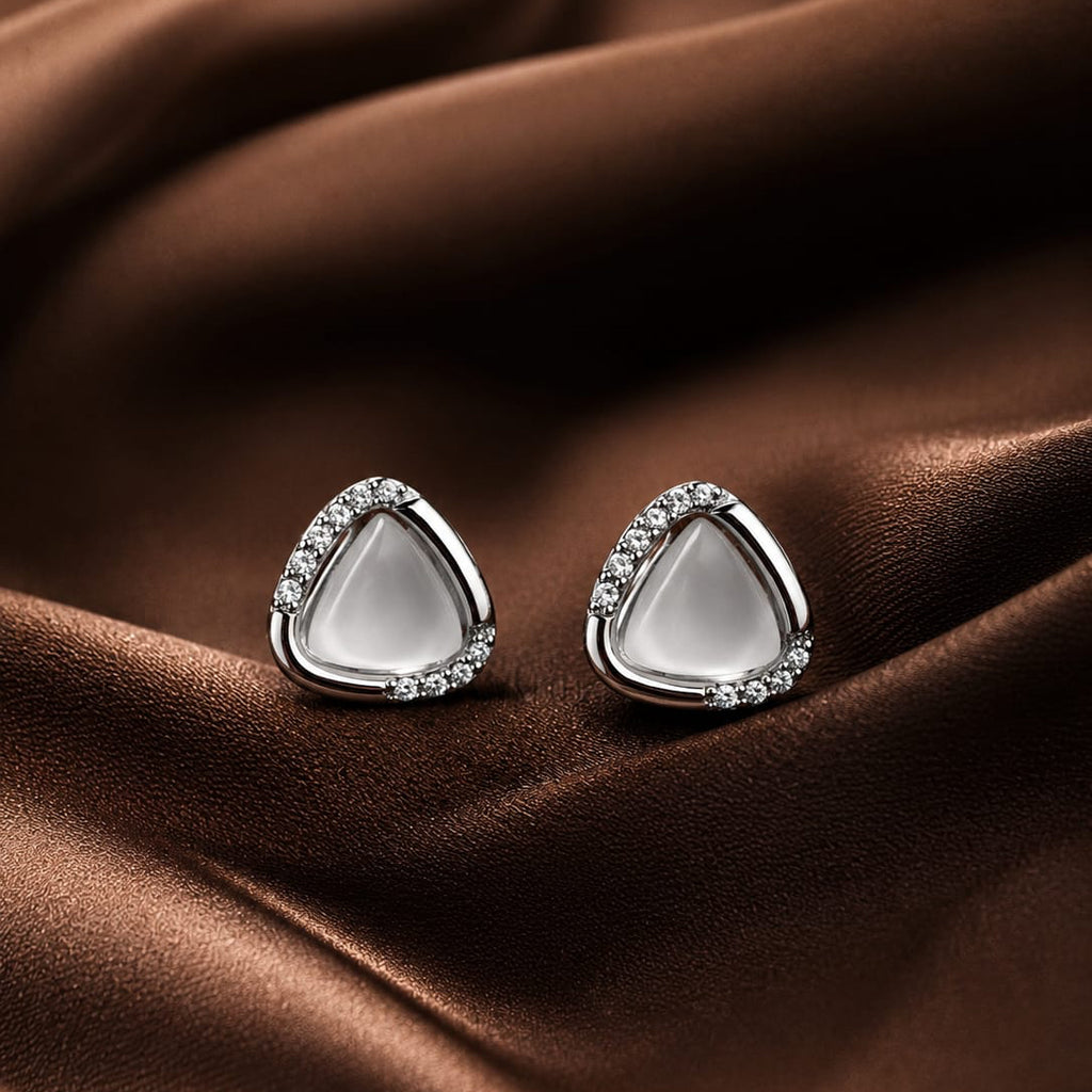Teardrop-shaped earrings with clear stones on a brown fabric background