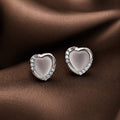 Heart-shaped earrings with embedded stones on a brown fabric background