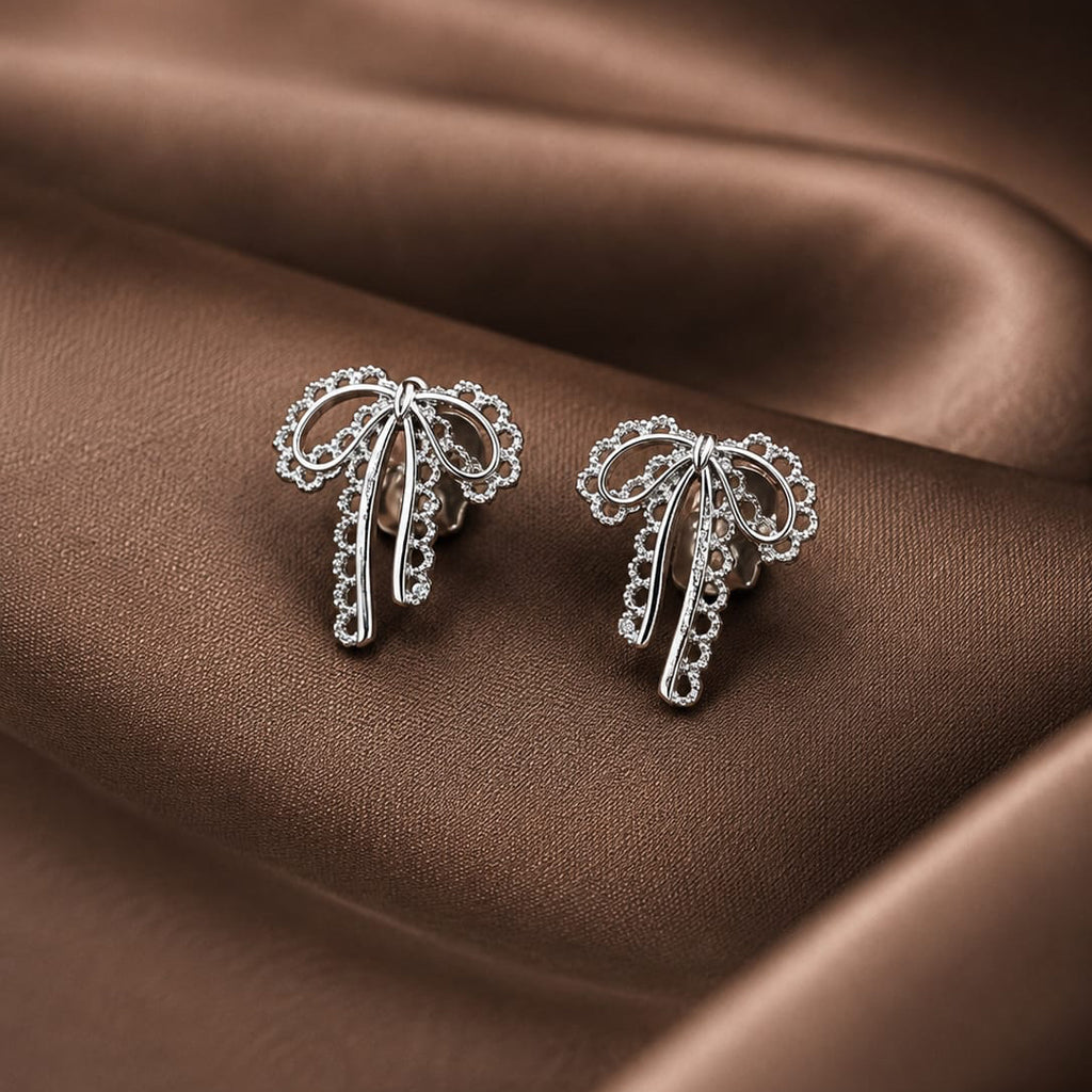 Silver palm tree earrings on a brown fabric background