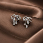Silver palm tree earrings on a brown fabric background