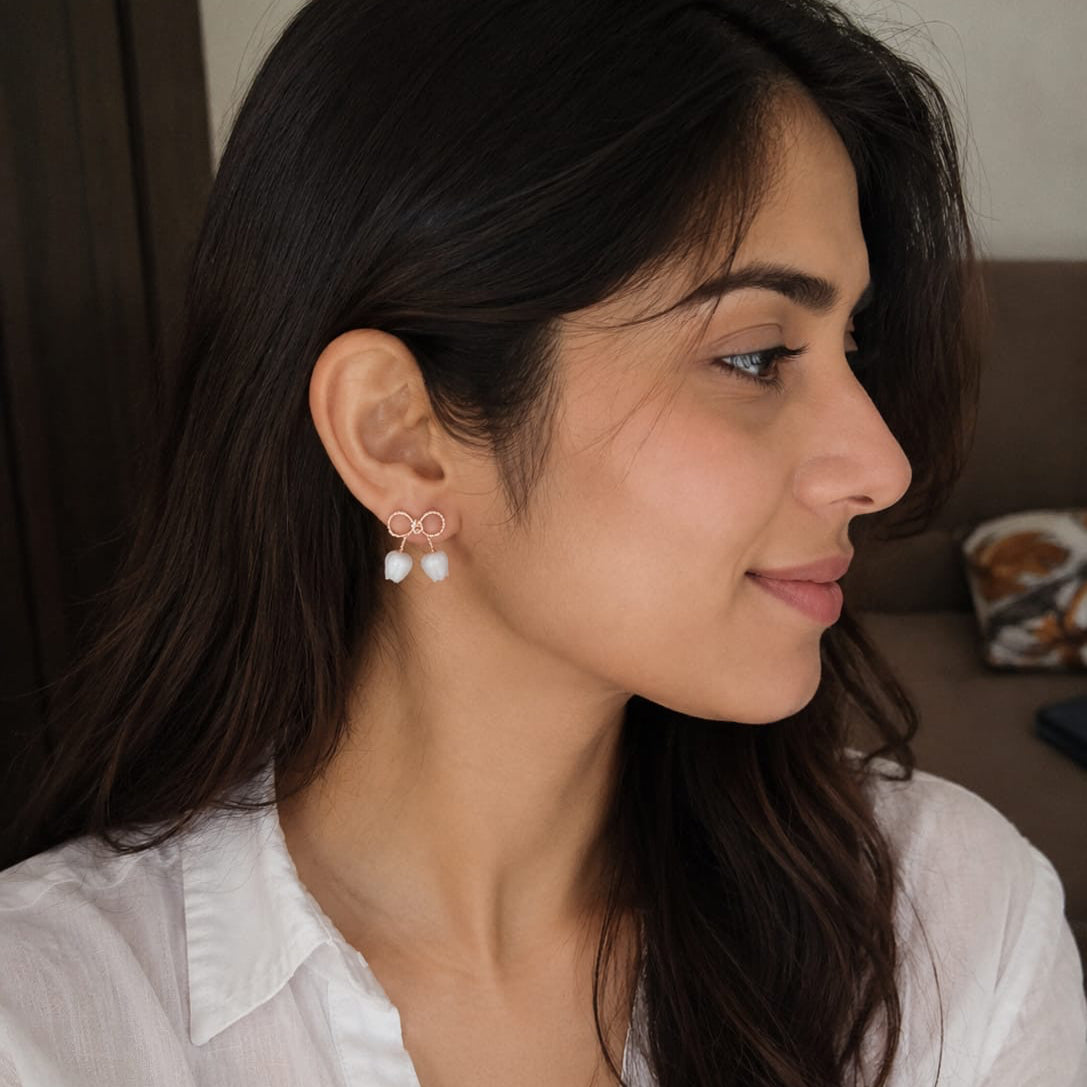 Woman wearing a pair of earrings with a neutral background