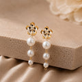 Gold earrings with pearl drops on a beige stone surface