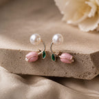 Pair of earrings with pearls and pink gemstones on a beige stone surface.
