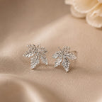 Silver leaf earrings on a beige fabric background