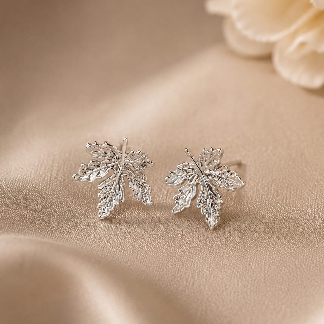 Silver leaf earrings on a beige fabric background