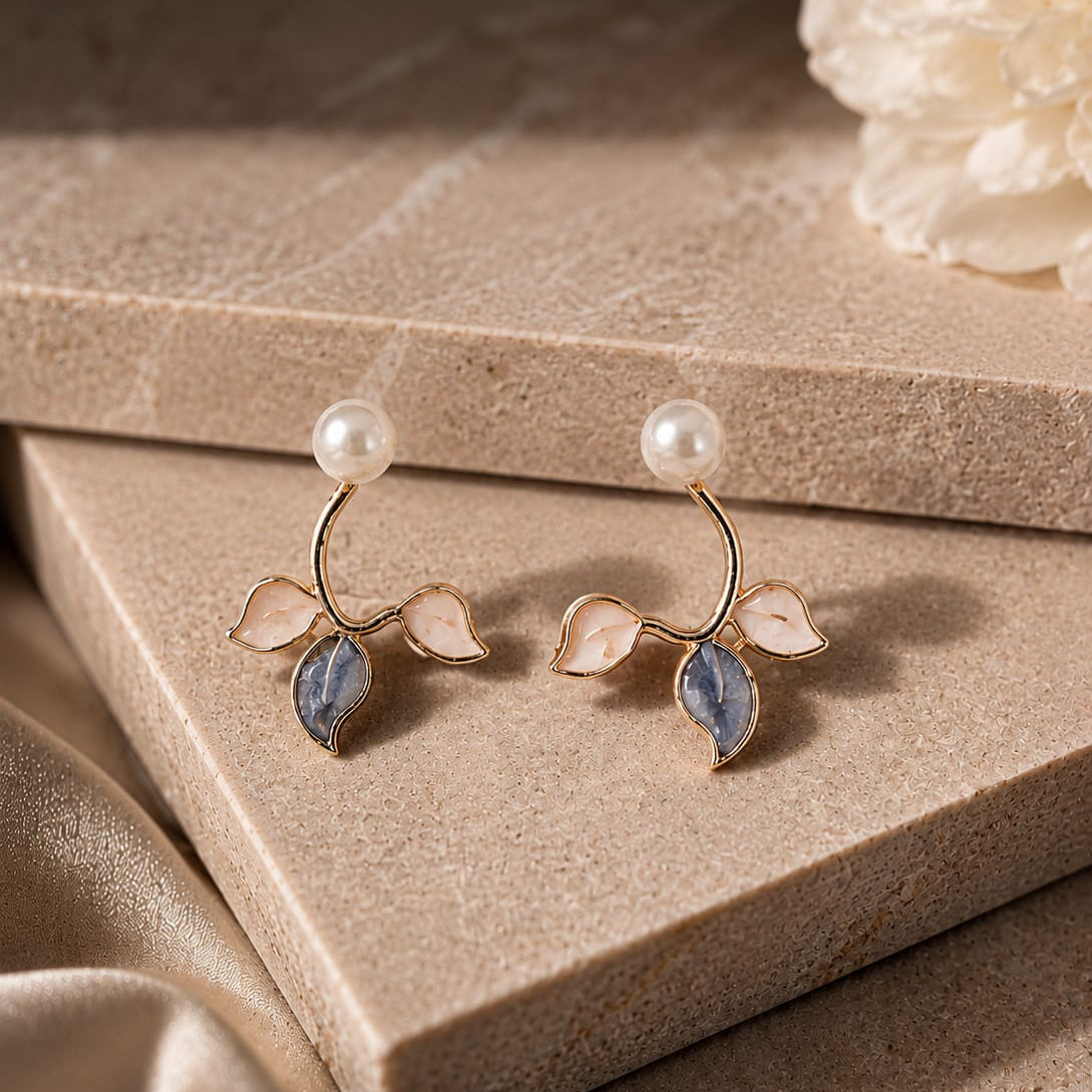 Pair of earrings with leaf design on a beige surface