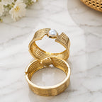 Gold bangle
 with a pearl on a marble surface
