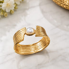 Gold ring with a pearl on a marble surface with flowers in the background