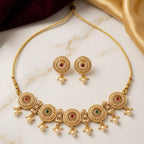 Gold necklace and earrings set on a marble surface