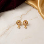 Gold earrings with red gemstones on a marble surface