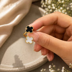 Hand holding a ring with a clover design against a neutral background