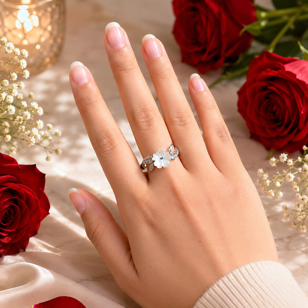 Hand wearing a floral ring with red roses and candles in the background
