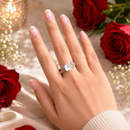 Hand wearing a floral ring with red roses and candles in the background