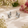 Butterfly earrings on a soft fabric background with flowers