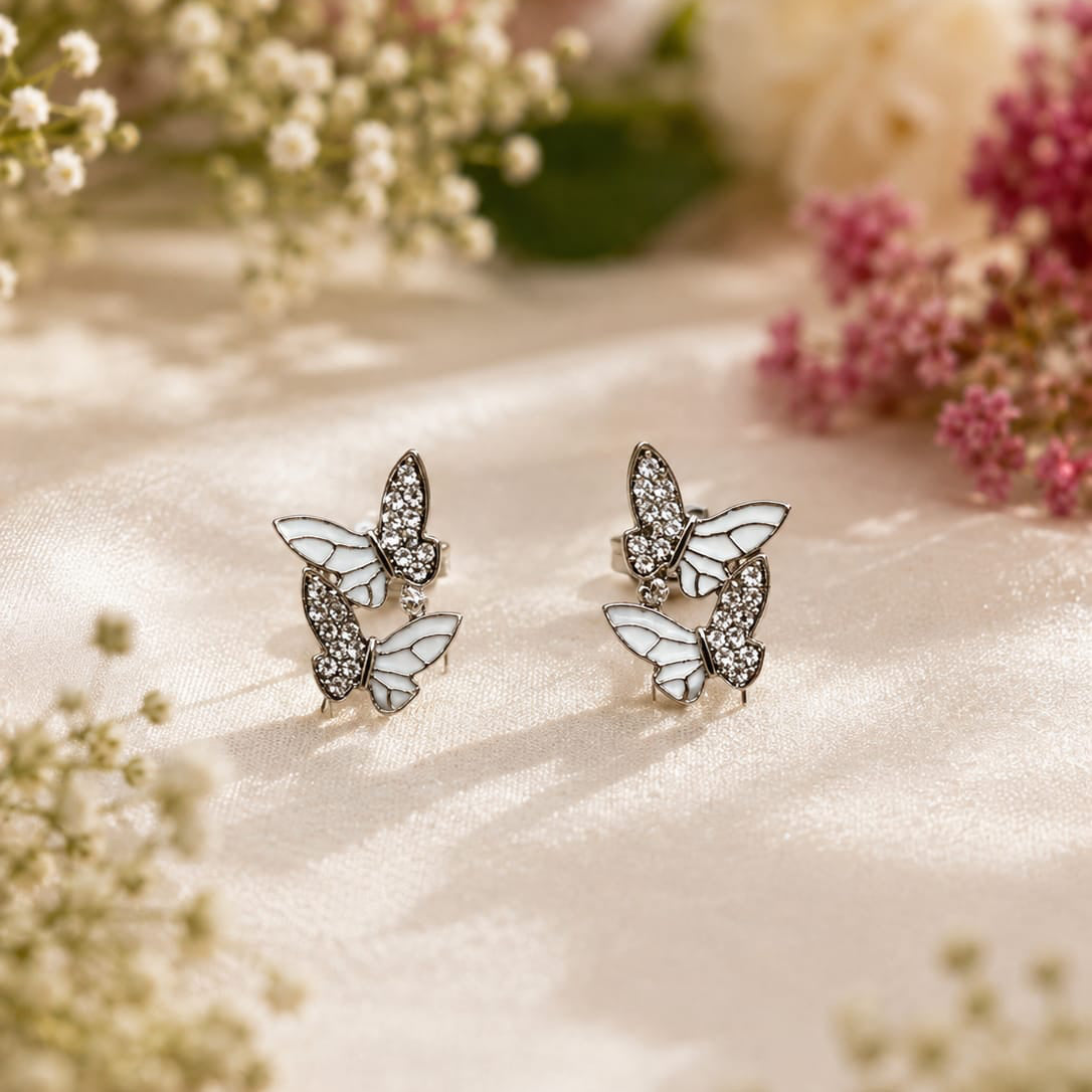 Butterfly earrings on a soft fabric background with flowers