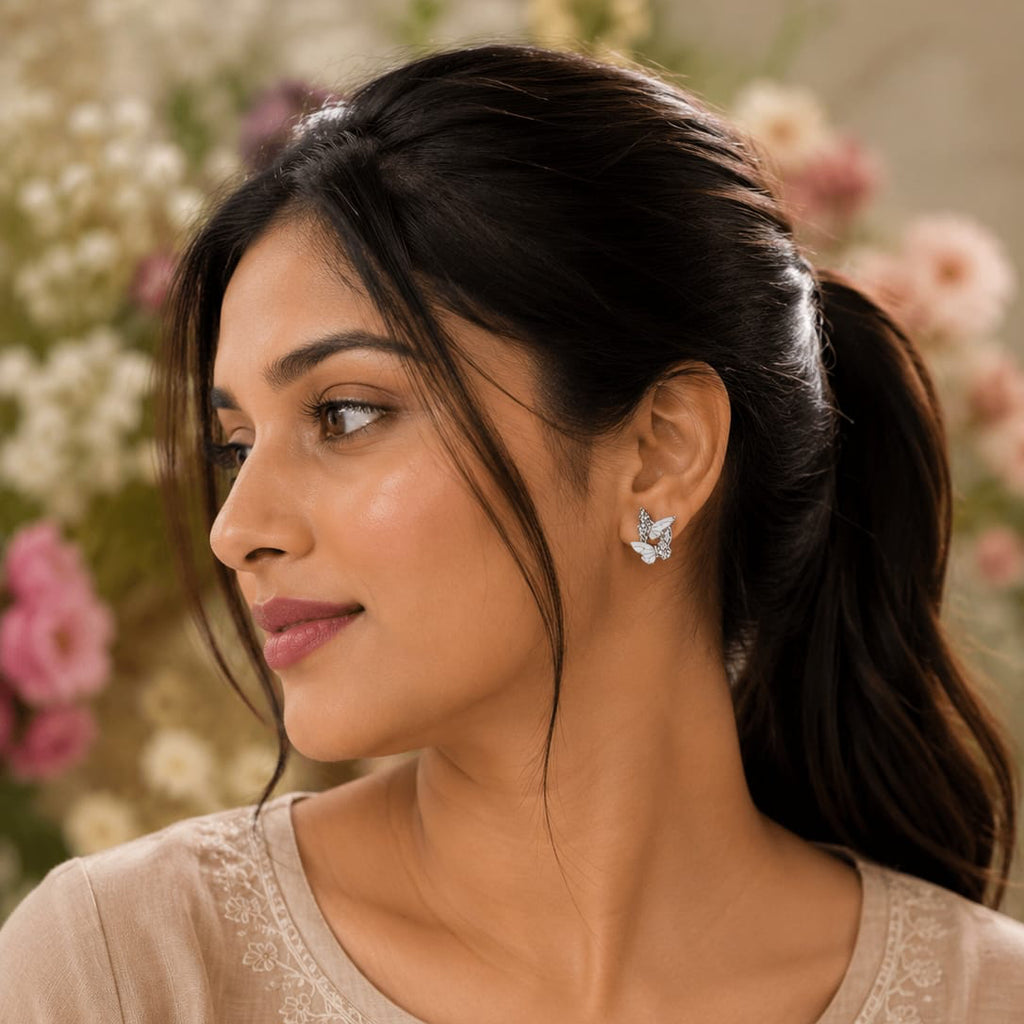 Woman wearing butterfly earrings with a floral background