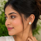 Woman wearing a floral earring with a blurred green background