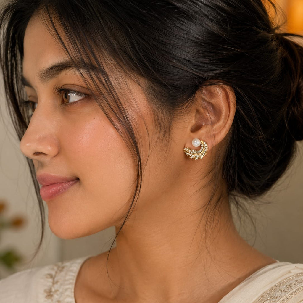 Woman wearing a white saree with gold embroidery, close-up of her ear with an earring.