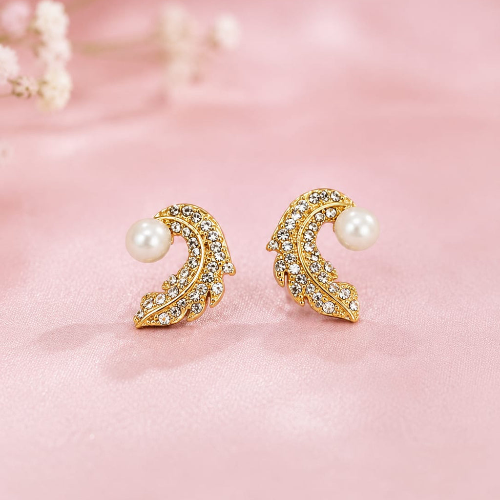 Gold earrings with pearls on a pink background