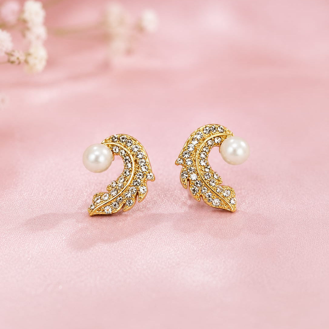Gold earrings with pearls on a pink background