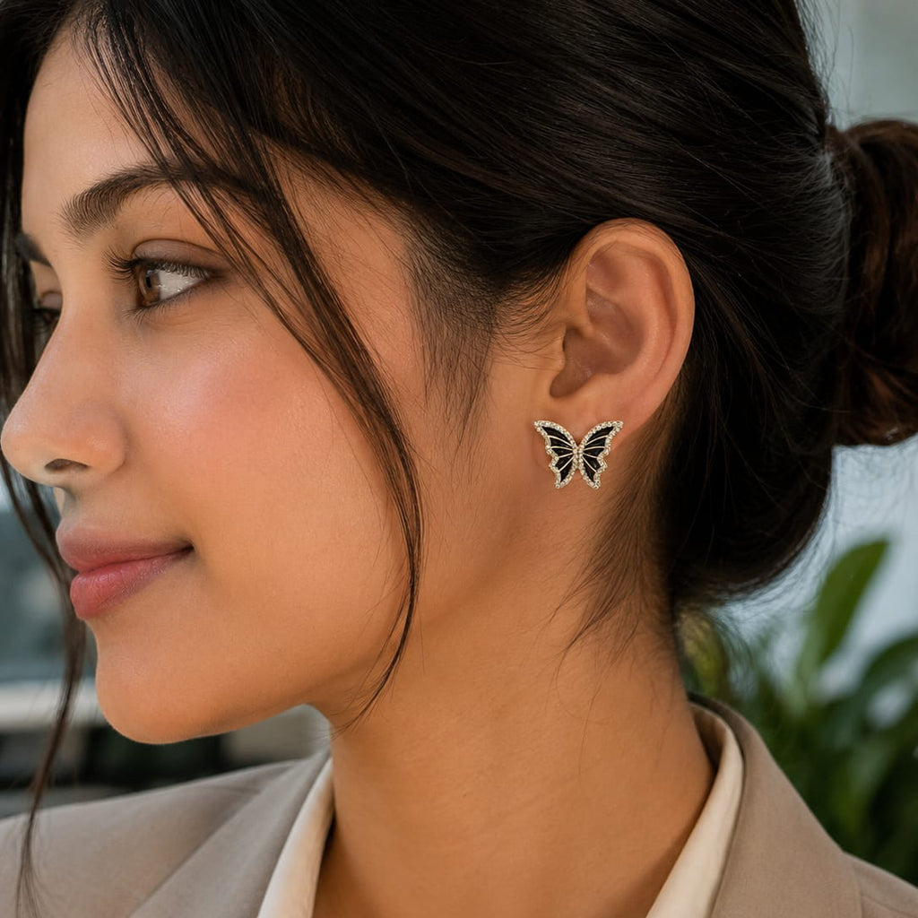Woman wearing butterfly earrings with a blurred outdoor background