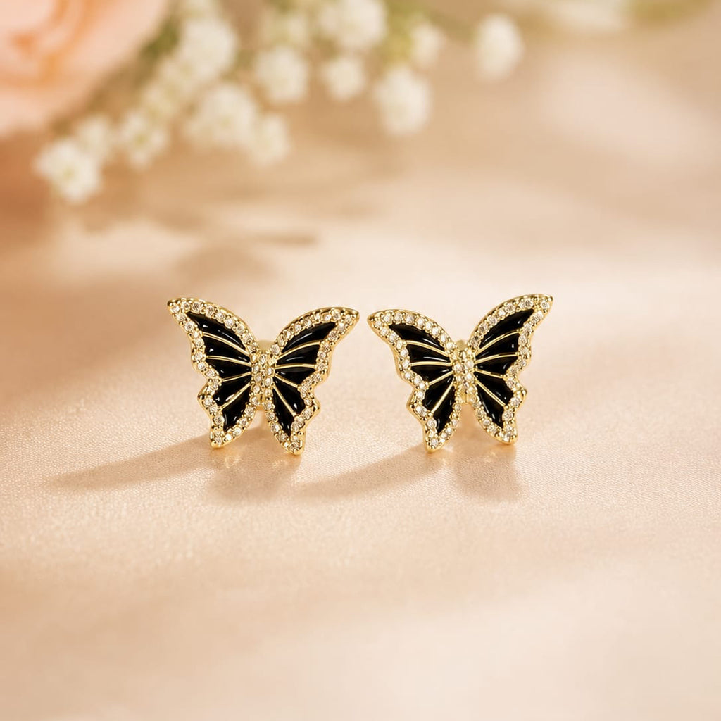 Butterfly-shaped earrings on a soft pink background with flowers.