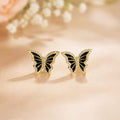 Butterfly-shaped earrings on a soft pink background with flowers.