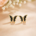 Butterfly-shaped earrings on a soft pink background with flowers.