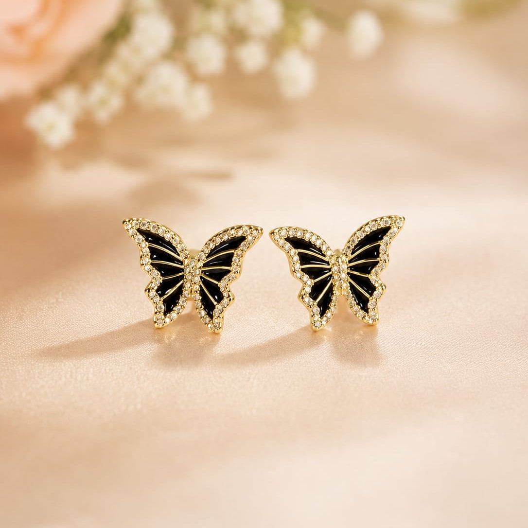 Butterfly-shaped earrings on a soft pink background with flowers.