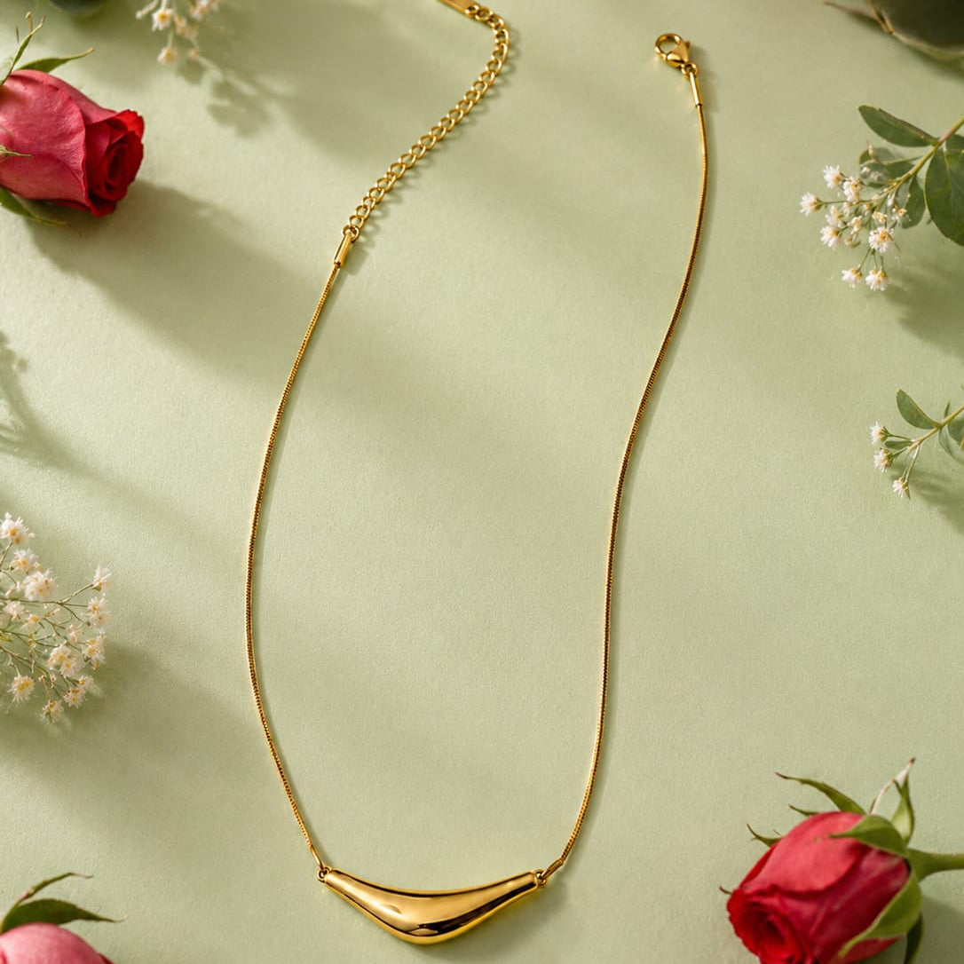 Gold necklace on a light green background with red roses and green leaves.