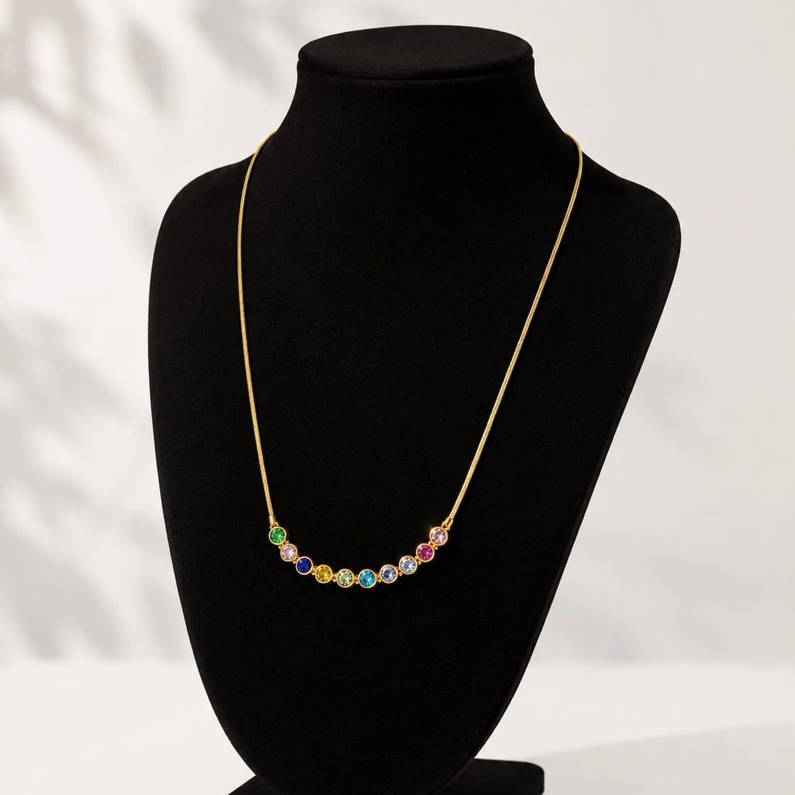 Necklace with multicolored beads on a black mannequin bust against a white background