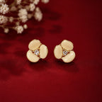 Gold floral earrings with gemstones on a red background