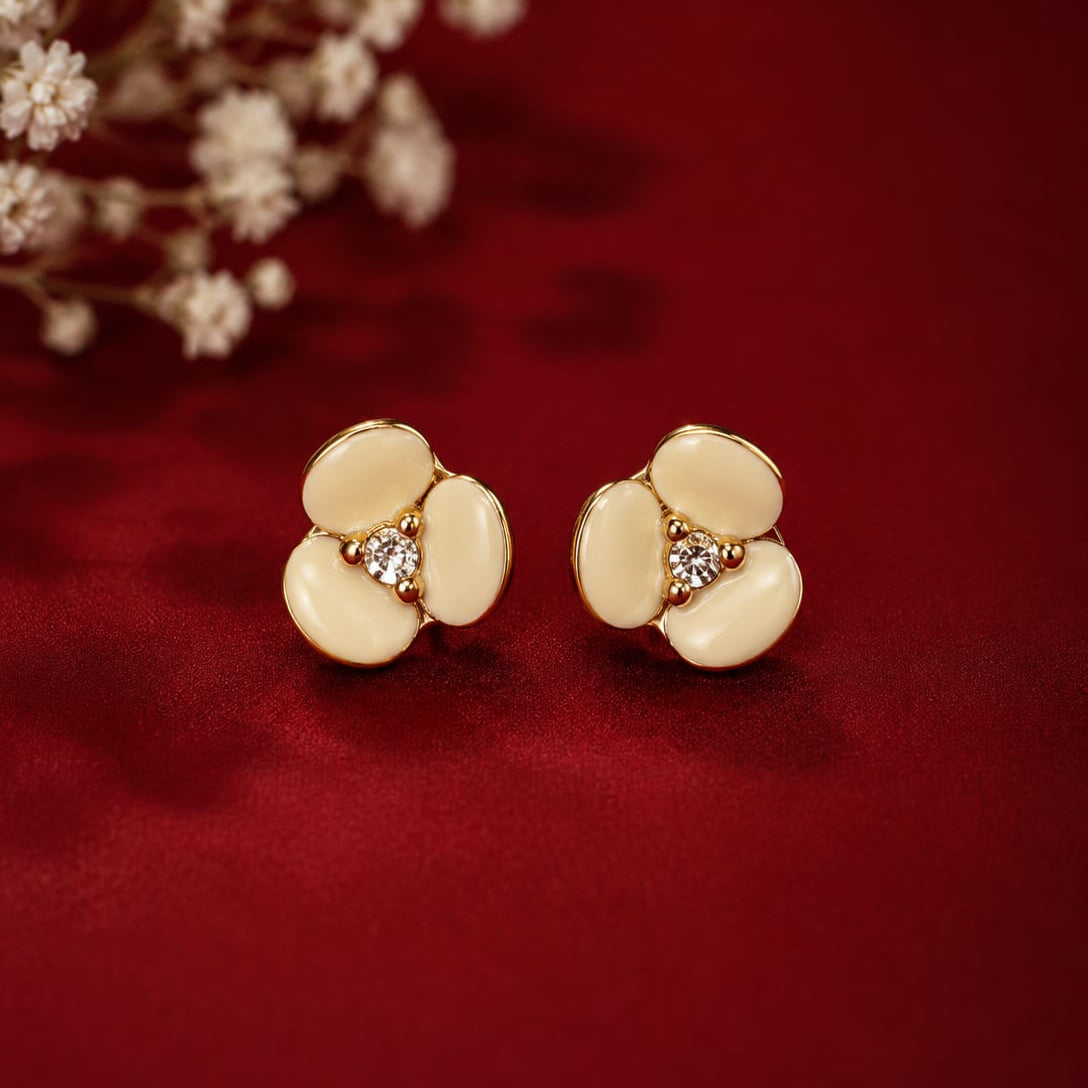 Gold floral earrings with gemstones on a red background