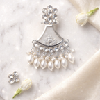 Silver and pearl jewelry set on a marble surface with flowers.