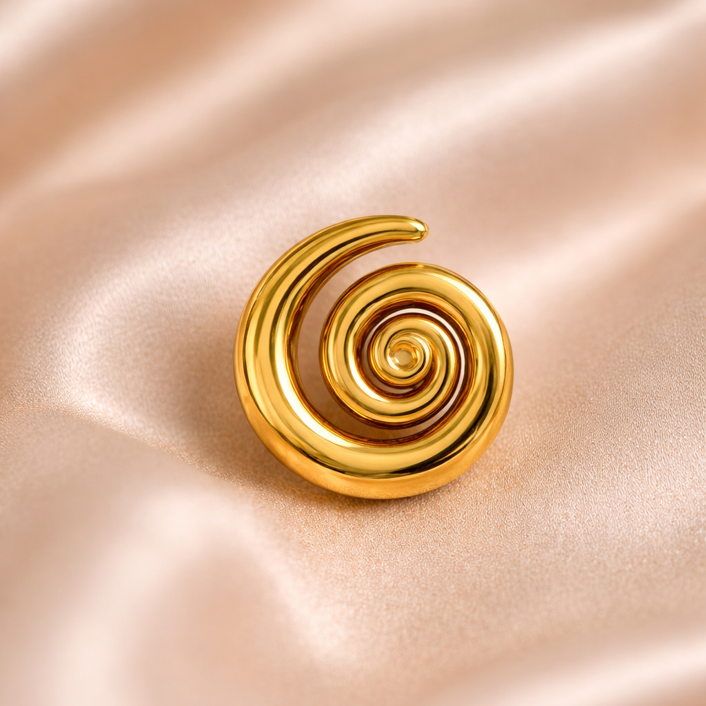 Gold spiral brooch on a pink satin background