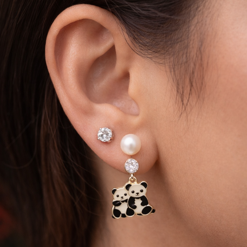 Close-up of an ear wearing a panda-themed earring with a pearl and gemstone.
