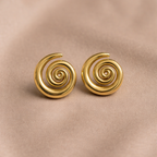 Pair of gold spiral earrings on a beige fabric background