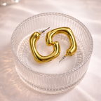 Gold hoop earrings on a textured glass dish with a soft light background