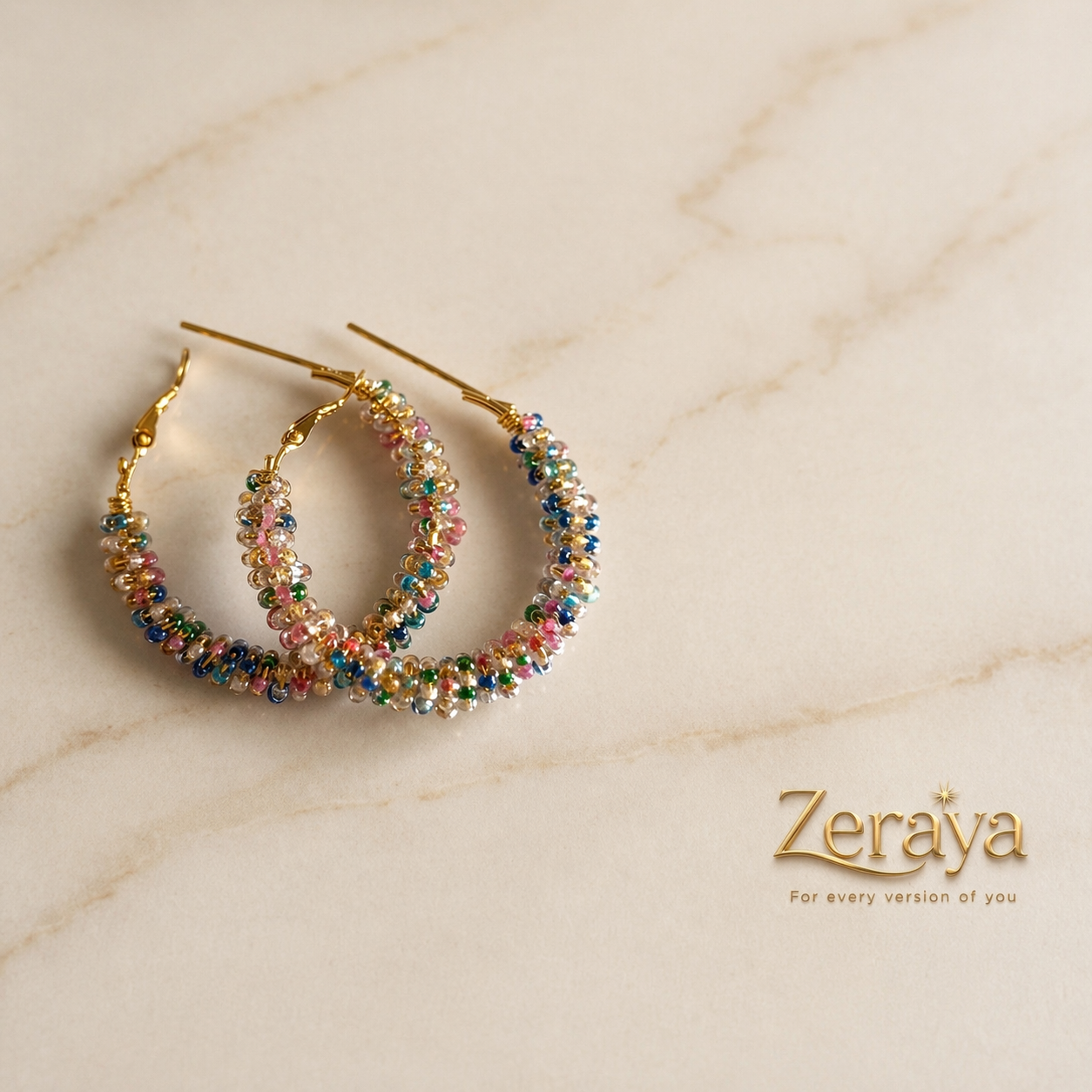 Colorful beaded hoop earrings on a marble surface with 'Zeraya' branding.
